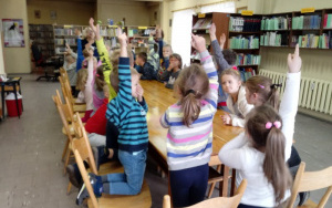 Dzieci podnoszą do góry rękę sygnalizując chęć odpowiedzi na pytanie konkursowe