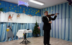 Pan Jacek w czarnym garniturze i muszce gra na skrzypcach