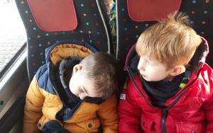 dwaj zmęczeni chłopcy  na siedzeniach w autkarze