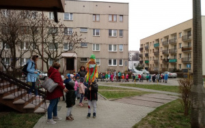 Kolorowa parada przedszkolaków z kwiatami i Marzanną przechodzi między blokami na osiedlu