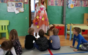 nauczycielka w kwiecistej sukni Pani Wiosny wchodzi do sali przedszkolaków