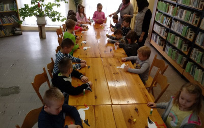 dzieci przy stolikach wykonują z papieru bociany