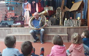 Mężczyzna prezentuje przedszkolakom instrument dęty
