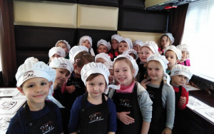 dzieci wstrojach kucharskich stojąusmiechnięte w grupie, oczekująna czekoladki