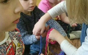 skupione dzieci zaplatują sznurkową włóczkę na paluszki