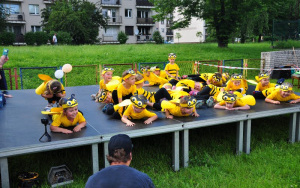 dzieci przebrane za pszczółki leżą na scenie na brzuchu i wymachują nogami