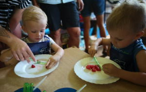 dzieci kroją plastikowymi nożykami owoce na talerzykach