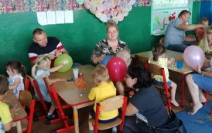 dzieci i rodzice przy stolikach wspólnie ozdabiają balony