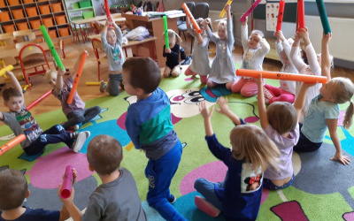 dzieci na dywanie podczas zabawy kolorowymi bumbum rurkami