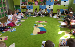 6. latki siedzą na dywanie, oglądają z zainteresowaniem otrzymane książeczki