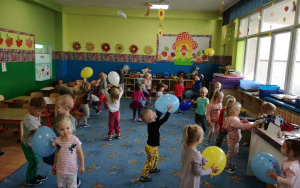 dzieci podrzucają do góry kolorowe baloniki