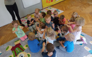 dzieci siedzą na dywanie, bardzo uważnie oglądają swoje rączki