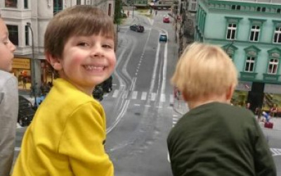 chłopcy oglądają makietę miasta - po lewej i prawej stronie budynki, pośrodku ulica, na niej samochody