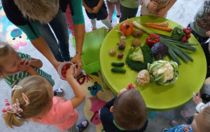 dzieci przy stoliku z warzywami, nauczycielka częstuje je koktajlowymi pomidorkami