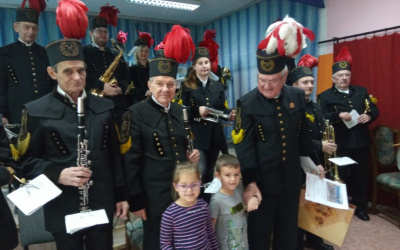 orkiestra górnicza wraz z chłopcem i dziewczynką pozuje do zdjęcia oraz otrzymanym upominkiem i dyplomem