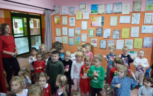 4, latki z filii śpiewają piosenkę dla Mikołaja, obok stoi Pani Renia w czerwonej bluzce