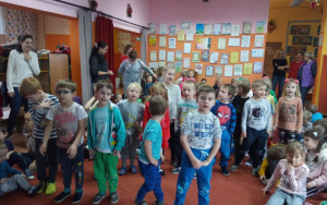 Dzieci z grupy 5, - 6, latków wraz ze swoą Panią w białym swetrze śpiewają piosenkę dla Mikołaja