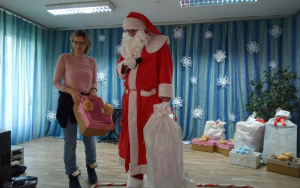 Mikołaj trzyma worek z prezentami, Pani Ania odbiera prezent dla maluszków