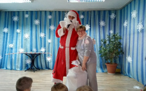 Uśmiechnięta Pani Iwonka pozuje do zdjęcia z Mikołajem od którego otrzymała prezenty dla grupy 5, latków
