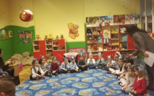 dzieci z grupy 4, latków siedzą na dywanie w srebrnych koronach w półokręgu