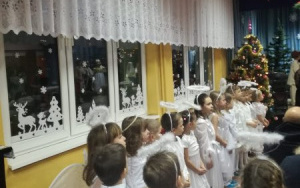 grupa dziewczynek w stroach aniołów stoi pod oknem zwrócona twarzami w kierunku sceny