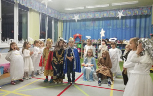 na dywanie grupa dzieci, aniołowie stoją w półokręgu, pośrodku Józef, Maryja oraz trzej królowie