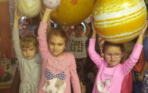 Grupka dzieci trzyma w wyciągniEtych nad głowę rękach atrapy planet