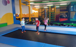 trójka dzieci skacze na czarnej trampolinie