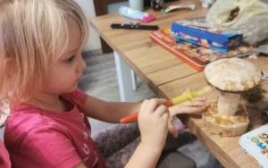 Dziewczynka maluje nóżkę grzyba farbą na żółty kolor