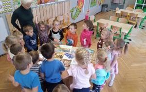 nauczycielka zadaje dzieciom zagadki związane z postaciami z bajek. Dzieci zgromadzone dookoła stolika z baśniami
