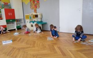dzieci układają puzzle z postaciami z bajek na podłodze