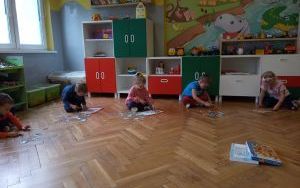 dzieci układają puzzle z postaciami z bajek na podłodze