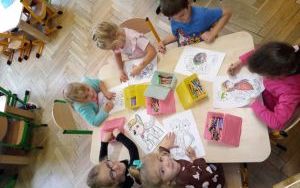 grupka dzieci przy stoliku koloruje postaci z bajek
