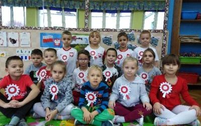 grupa dzieci z białoczerwonymi kotylionami pozuje do zdjęcia