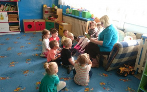Dzieci siedzą na dywanie i słuchają czytania