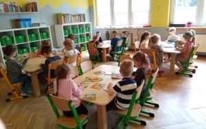 dzieci przy stolikach oglądają kolorowe książeczki