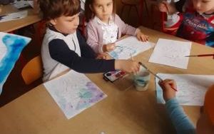 dzieci przy stolikach kolorują wiosenne obrazki