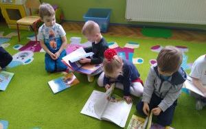 dzieci na dywanie oglądają książeczki