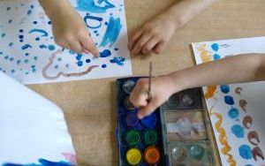 dzieci malują akwarelamii za pomocą palców i pędzelka
