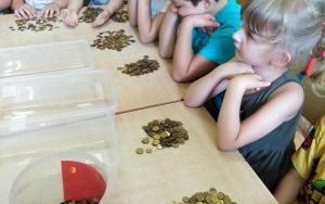 dzieci przy stolikach segregują monety po zbiórce
