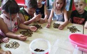dzieci przy stolikach segregują monety po zbiórce (2)