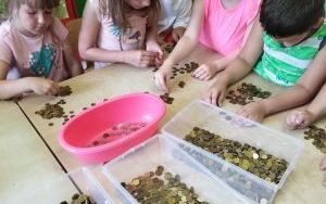 dzieci przy stolikach segregują monety po zbiórce (3)