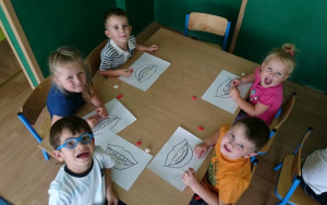 piątka dzieci wykleja obrazek plasteliną