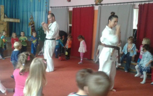 dzieci w kole, mężczyna i kobieta prezentują umiejętności karate