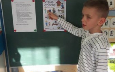 chłopec wskazuje jedno z praw dzieci podczas zajęć, na plakacie