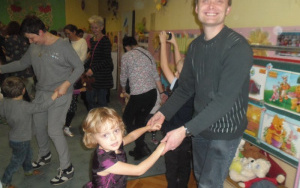 dziewzynka tańczy z tatą w tle inne dzieci i rodzice